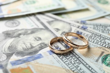 Two gold wedding rings on dollar banknotes, closeup