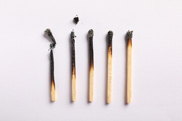 Burnt matches on light grey background, flat lay