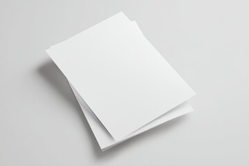 A blank white A4 flyer mockup shot from an angled top-down perspective, laying slightly rotated on a clean light gray surface, no text or branding, matte paper texture, soft natural lighting