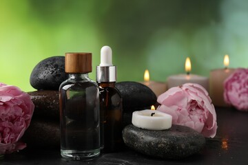 Spa composition with wet stones, cosmetic products and burning candles on dark table against blurred green background, closeup