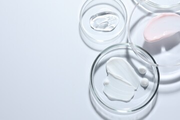 Different cosmetic products in Petri dishes on white background, flat lay. Space for text