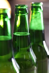 Bottles of beer on blurred grey background, macro view