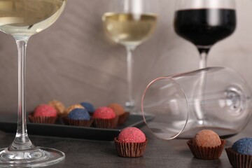 Tasty wine in glasses and truffle bonbons on grey table, closeup