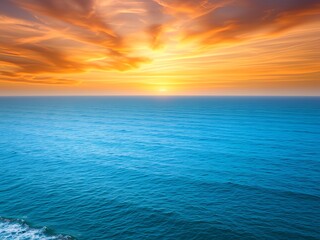 Fototapeta premium Vibrant sunset over a calm blue ocean with dramatic clouds