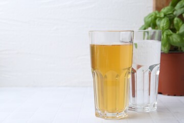 Glasses with clean and dirty water on white tiled table, closeup. Space for text