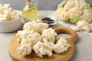 Fresh raw cauliflower florets and spices on light grey table, closeup