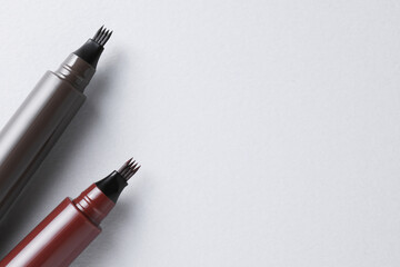 Liquid eyebrow pencils on white background, above view. Space for text