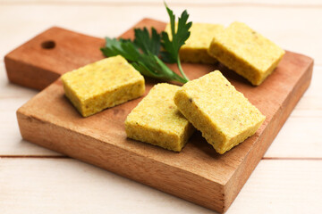 Aromatic bouillon cubes and parsley on wooden table, closeup