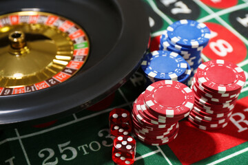 Casino chips, dice and roulette wheel on table, closeup