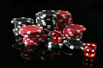 Casino chips and dice on mirror surface against black background, closeup