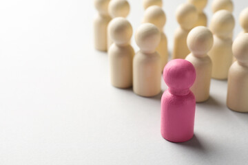 Unemployment. One pink figure among wooden on light background, closeup. Space for text