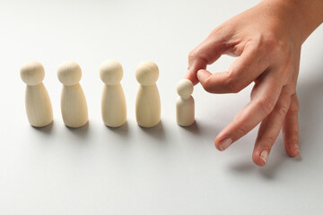 Dismissal. Woman throwing one human figure away on light background, closeup