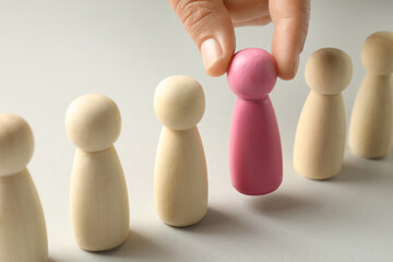 Dismissal. Woman taking one human figure away on light background, closeup