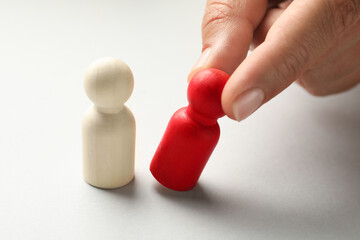 Dismissal. Woman taking one human figure away on light background, closeup