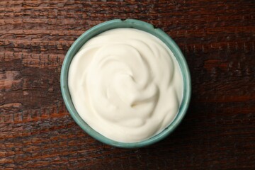 Tasty sour cream on wooden table, top view