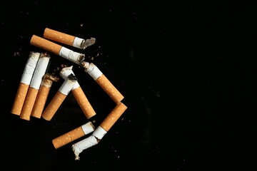 Cigarette butts with ash on black background, flat lay. Space for text