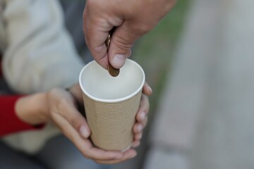 Man giving money to homeless people outdoors, closeup. Space for text
