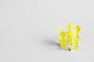 Human paper figures holding hands on light background. Space for text