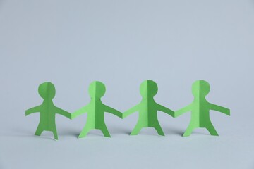 Human paper figures holding hands on light background