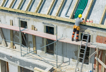 Worker Installing Roof Support at a Construction Site in Broad Daylight