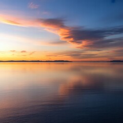 Fototapeta premium Sunset over calm water with distant mountains ocean