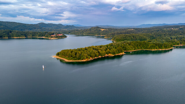 Aerial view of a forested peninsula on Lake Solina in the Bieszczady Mountains. Scenic summer landscape with calm water and mountain backdrop near Polańczyk.