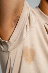 excessive sweating concept. Close-up of a person's upper arm wearing a light-colored garment,...