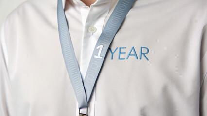 Happy Work Anniversary and thank you. Employee wearing a shirt with a lanyard indicating one year of service.
