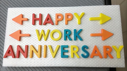 Happy Work Anniversary and thank you. Colorful letters spell out "Happy Work Anniversary" with arrows, celebrating a milestone in the workplace.