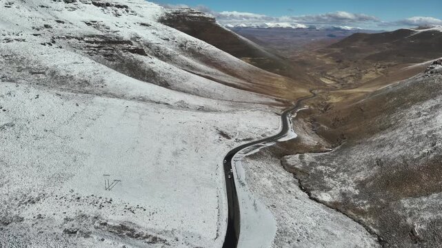 Aerial footage captures a remote, winding road cutting through thick snow on the Black Mountain Pass in Lesotho during July 2025. 