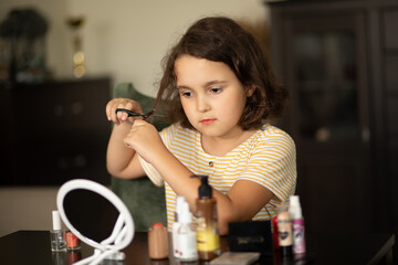 Cute little girl cutting her hair with scissors at home