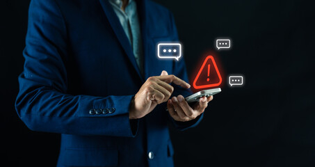 A man in a dark suit interacts with a smartphone displaying a red warning alert and chat icons...