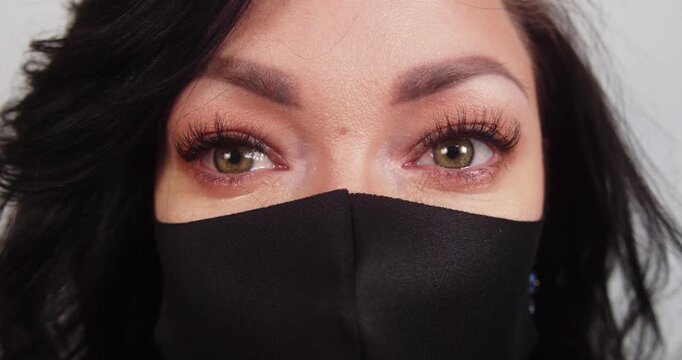 Woman in a black face mask with tears in her eyes