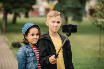 Girl and boy teenagers bloggers influencer records videos from the blog on a smartphone outdoor....