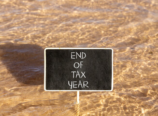 Naklejka premium End of tax year symbol. Concept words phrase End of tax year on beautiful black blackboard. Beautiful Red sea water background. Business End of tax year concept. Copy space.