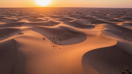 Aerial view of endless sand dunes in the desert at sunset. Golden hour light over a vast, arid landscape with rolling hills of sand. - Powered by Adobe
