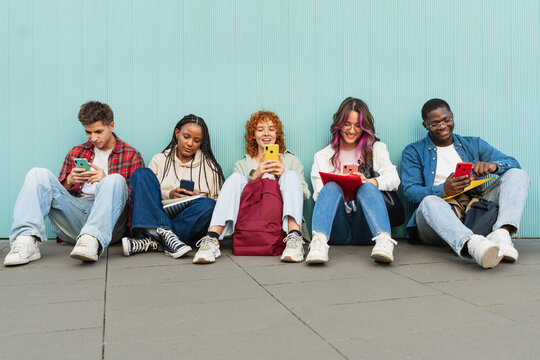 Happy friends using cell phones and social media - Students sitting in university campus using app on the smartphones