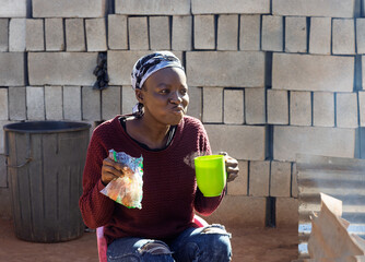 Africa village, hungry african woman eating potato chips, French fries takeaway ,and drinking hot...