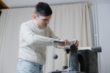 The guy is assembling a new cat house with hanging toys.