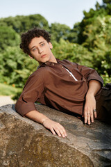 Curly haired young man enjoying a tranquil day in a vibrant summer park