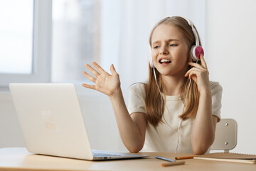 Young girl with headphones engaging in an online class, showcasing excitement and concentration...