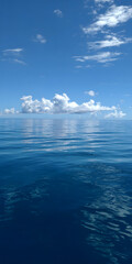 Obraz premium A beautiful blue ocean with a few clouds in the sky. The water is calm and clear