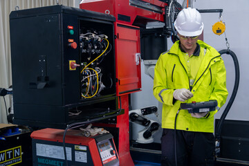 Technician performing maintenance on machinery in a manufacturing facility during daytime hours