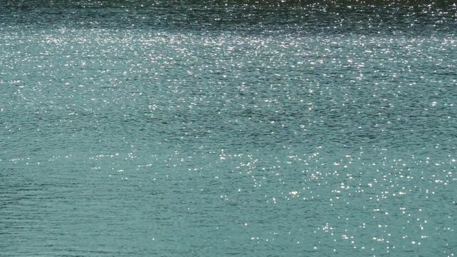 風でさざなみが立ったキラキラ光る水面の背景用素材。時間帯とボケの強弱のバリエーション。