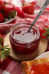 Tasty homemade strawberry jam, toast and berries on table, closeup