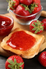 Toast with tasty homemade strawberry jam and berries on wooden table, closeup