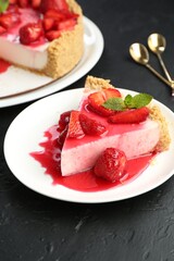 Piece of tasty cheesecake with strawberries, sauce and mint on black table, closeup