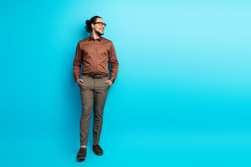 Confident young businessman in stylish formalwear posing against a vibrant teal background...