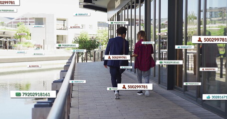 Walking on sidewalk, people surrounded by floating digital data tags in image