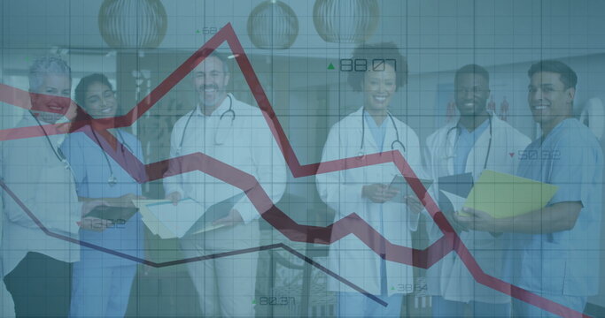 Medical team standing in hospital corridor, holding clipboards and showing falling financial graph